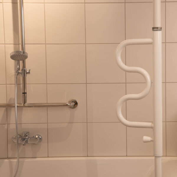 Weiße Stange, die zwischen Decke und Boden gespreizt werden kann. Durch Doppel-S-förmigen, schwenkbaren Haltegriff sehr viele Möglichkeiten zum Festhalten.