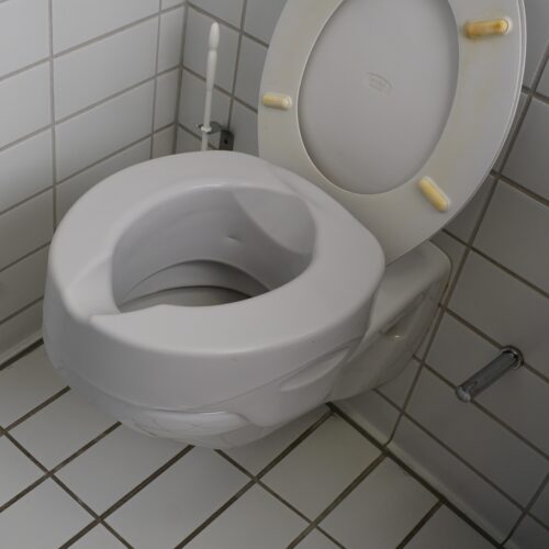 Die Toiletttensitzerhöhung ist auf eine weiße Keramik aufgesteckt.