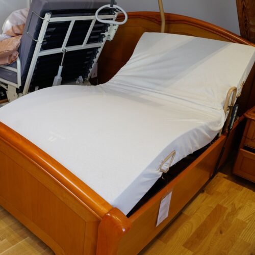 Der Einlegerahmen bildet eine Bettseite in einem Doppelbett-Gestell aus Holz. Kniee und Kopf sind hochgestellt.