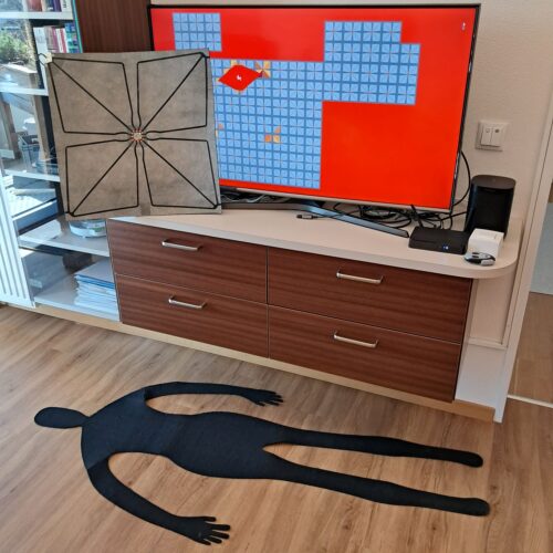Beispielhaft liegt ein Körperumriss auf den Boden. Am Bildschirm wird die Position angezeigt.