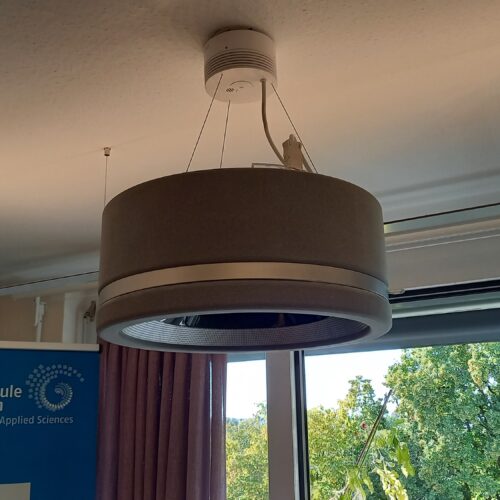 Abgehängte runde Lampe. Durchmesser circa 40 cm. Seitensteg 20 cm hoch, graue Textilbespannnung mit silbernen Streifen