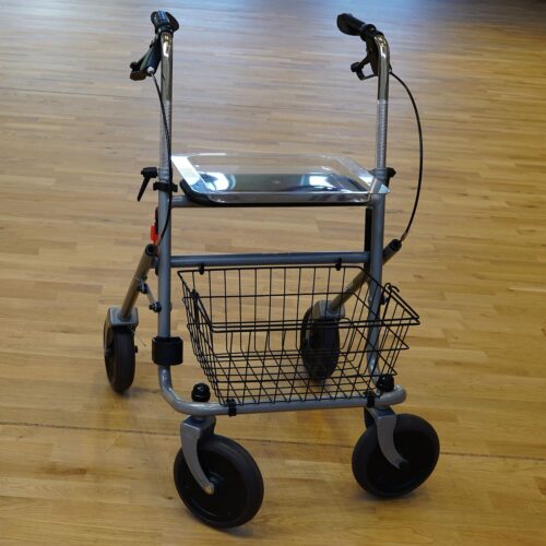 Einfacher grauer Rollator mit Einkaufskorb vorne, und Tabeltt oben auf. Durchmesser der Räder ca. 18 cm.