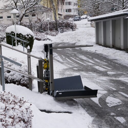 Der Plattformlift ist an der unteren Seite der Treppe. Zum Befahren sind die Seitenteile ausgeklappt.