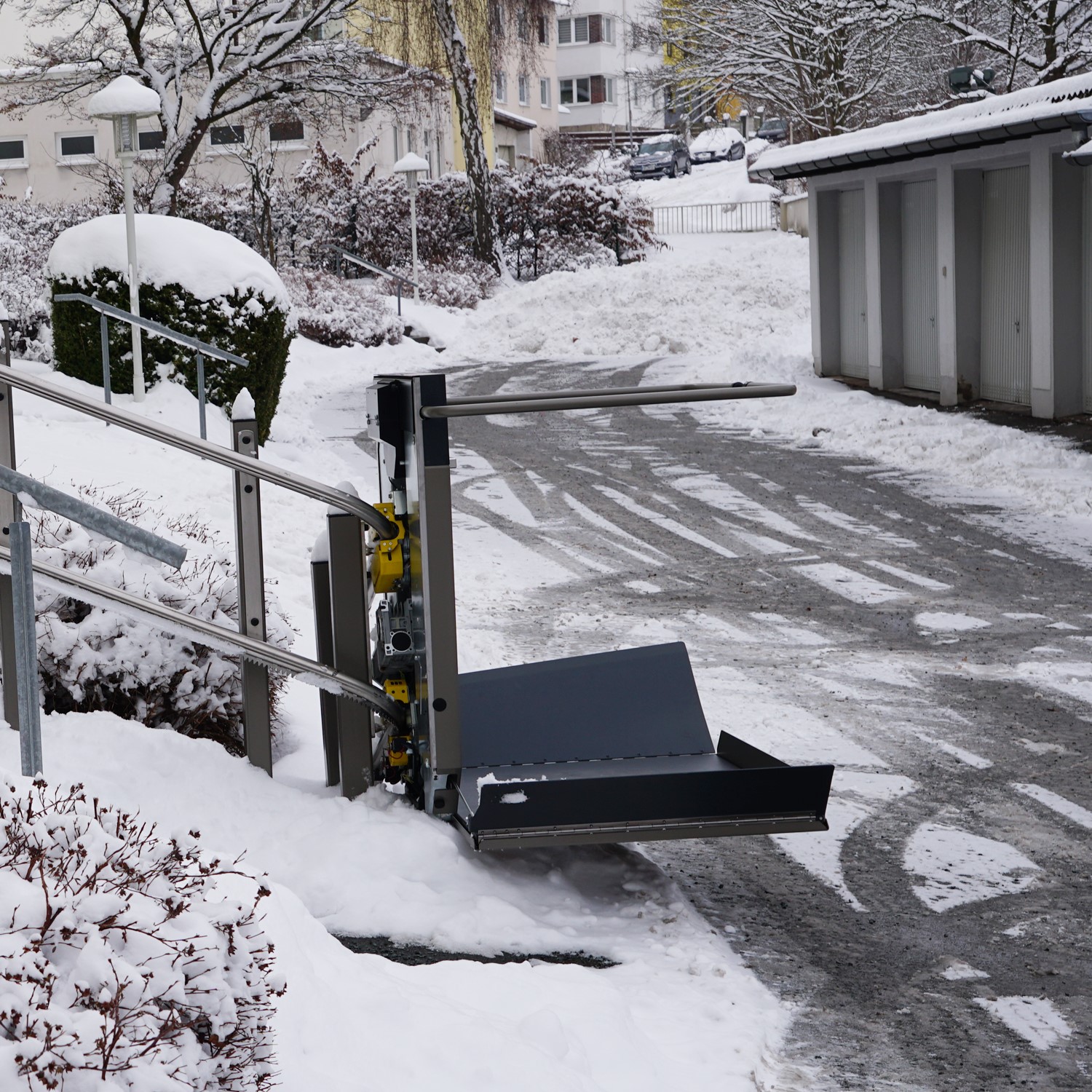 Der Plattformlift ist an der unteren Seite der Treppe. Zum Befahren sind die Seitenteile ausgeklappt.